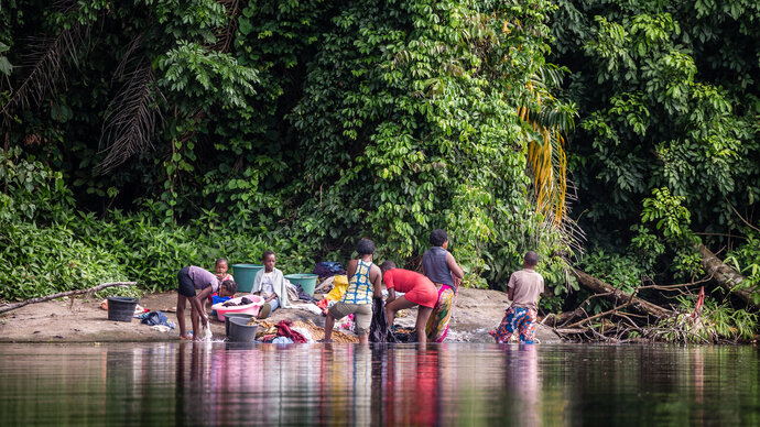 Photo of women and children washing in a lake