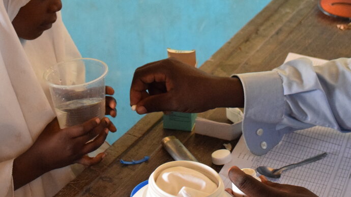 Deworming tablets being handed to a pupil. Image copyright Schistosomiasis Control Initiative