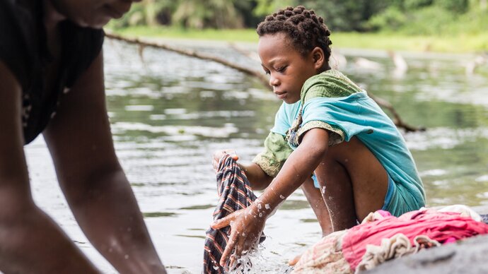 Young person washing clothes in water. cr. M Perkins