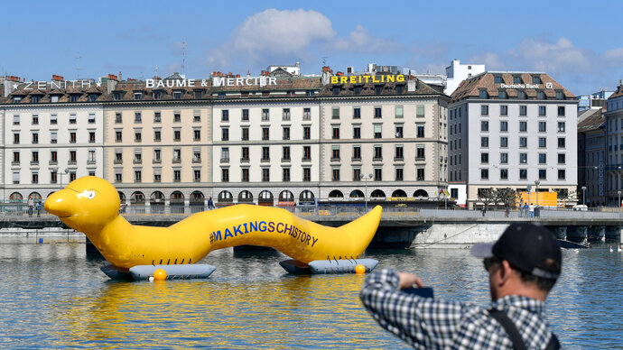 GSA News and Events Photo of an inflatable yellow worm floating on Lake Geneva, part of the Macking Schistory Campaign