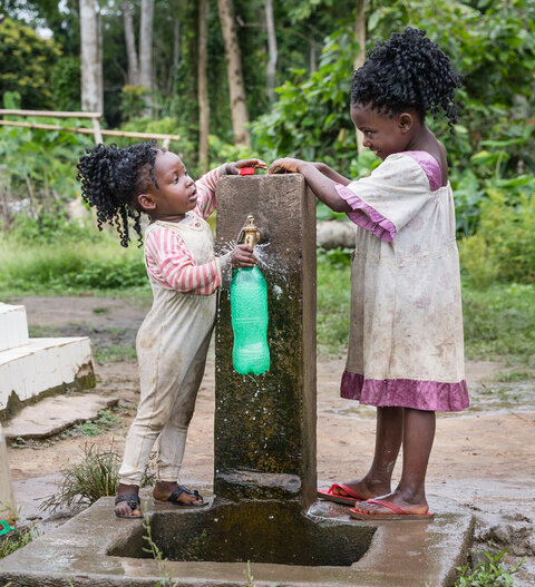 Two children collecting water from a tap