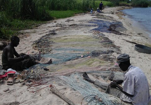Fishermen mending nets next to a lake. Copyright Anouk Gouvras