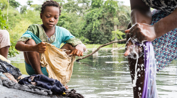 A child washes clothes by the river